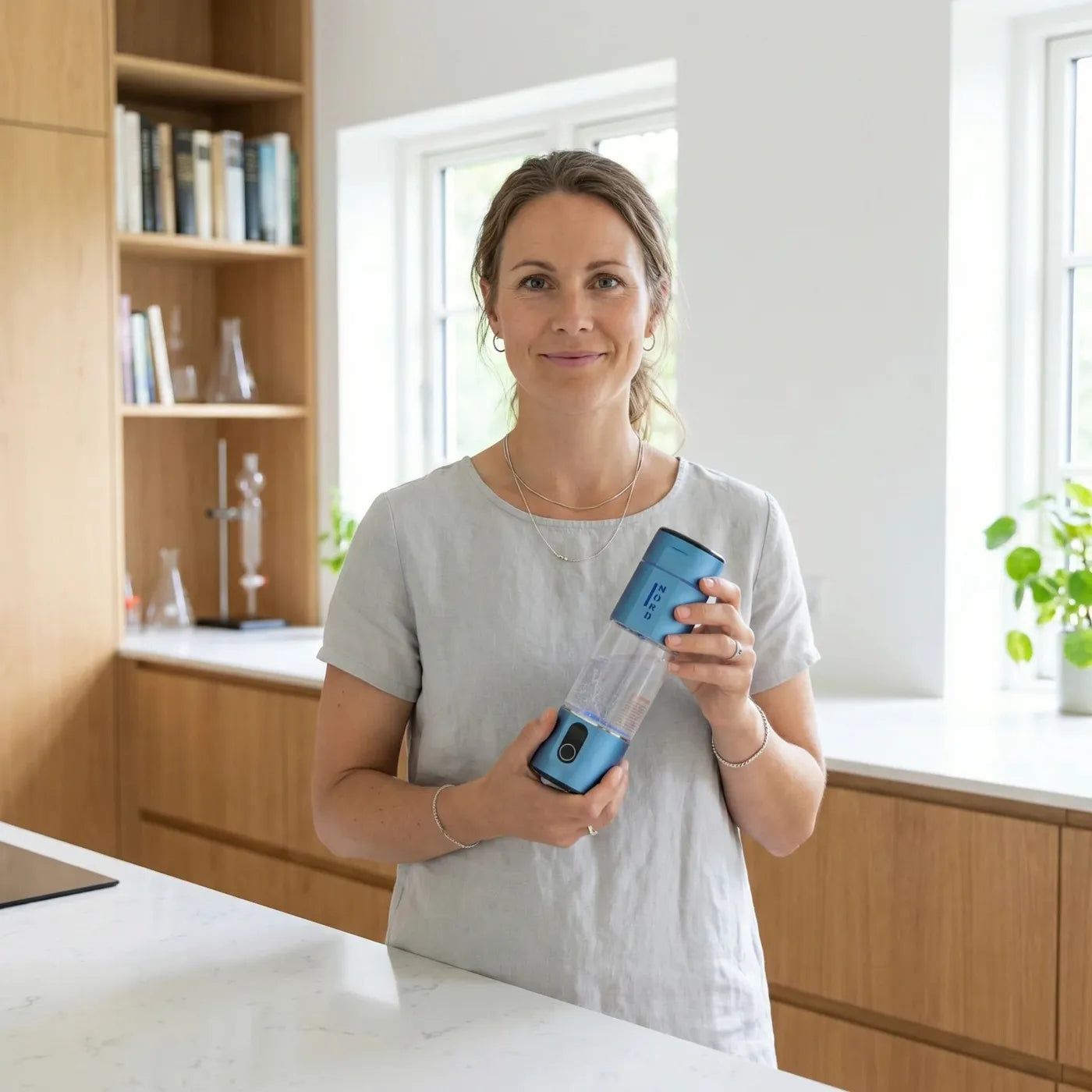 Kvinna i ett ljust kök som håller Nord Hydrogen Bottle i Deep Space Blue